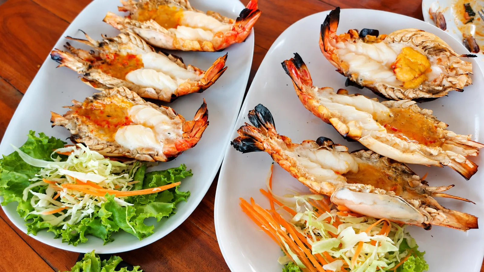 กุ้งเผาผ่าครึ่งเรียงบนจานพร้อมผักเคียงที่ครัวบ้านวัง